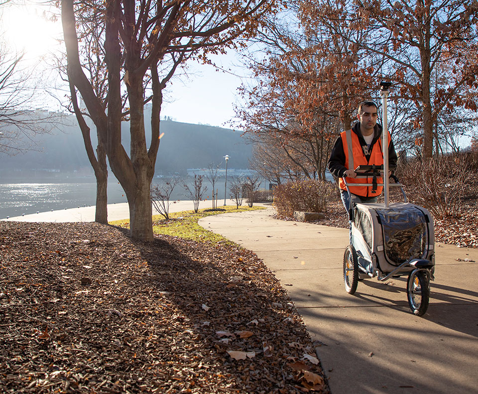 pathVu technician collects sidewalk data using pathMet near the allegheny river in Pittsburgh.