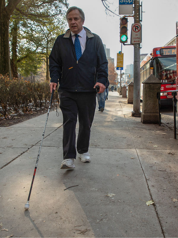 Image of a blind man walking on the sidewalk